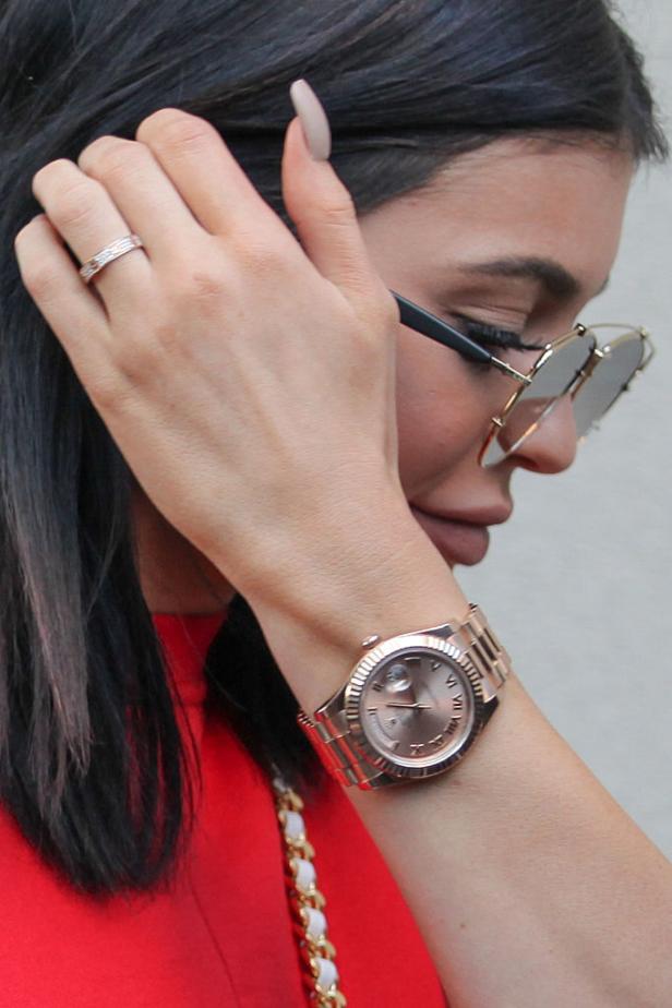 Nahaufnahme einer Frau mit Sonnenbrille, goldener Uhr und Ring.