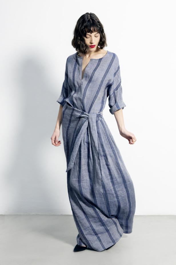 Eine Frau trägt ein blau-gestreiftes Leinenkleid mit Wickeldetail.