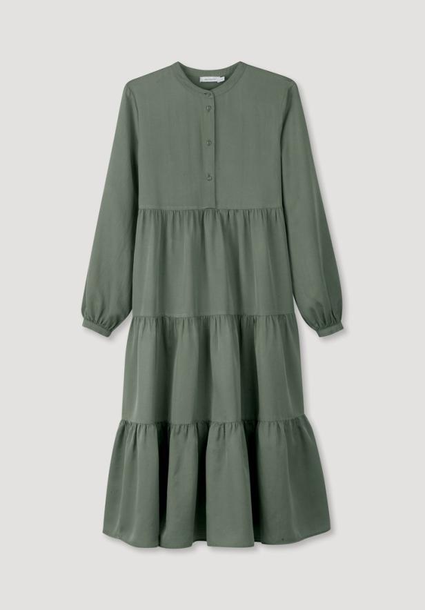 Ein grünes, gestuftes Kleid mit langen Ärmeln vor einem neutralen Hintergrund.