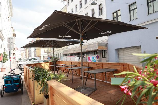 Einladende Terrasse eines Cafés mit Tischen und Sonnenschirmen auf dem Gehweg.