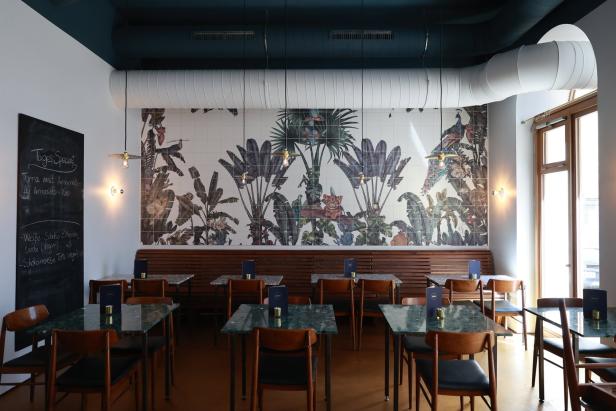 Ein Restaurant mit Tischen und Stühlen vor einer Wand mit Dschungelmotiven.