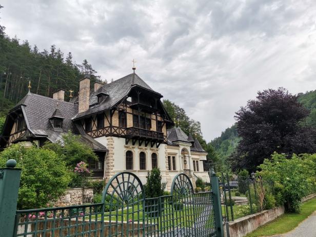 Ein großes Haus im traditionellen Stil mit einem grünen Zaun davor.
