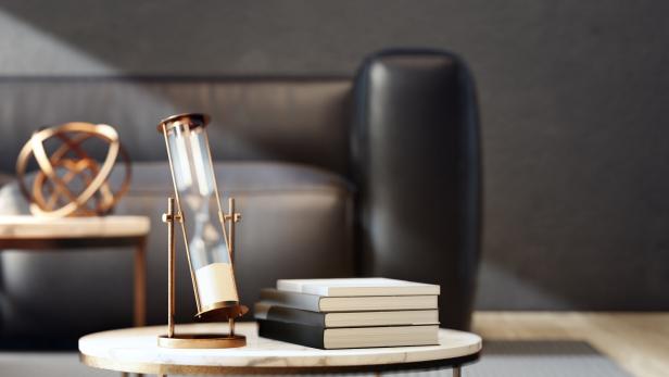 Eine goldene Sanduhr steht auf einem Tisch neben einem Stapel Bücher.