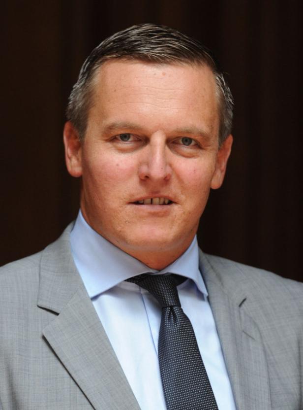 Ein Mann in Anzug und Krawatte blickt in die Kamera.