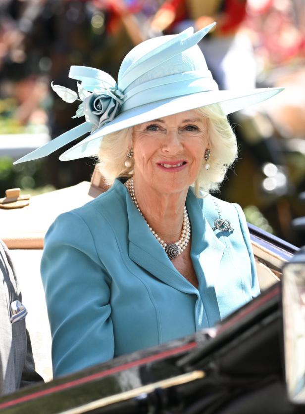 Königin Camilla trägt einen hellblauen Hut und eine passende Jacke.