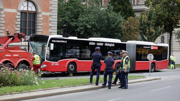 Ein beschädigter Bus der Wiener Linien wird von einem Abschleppwagen geborgen. Polizisten stehen daneben.