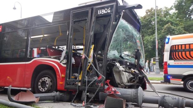 Ein roter Bus ist mit einer Straßenlaterne kollidiert, die Windschutzscheibe ist zerbrochen.