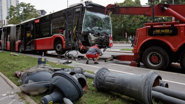 Ein beschädigter Bus wird von einem Abschleppwagen geborgen, während ein Arbeiter die Bergung überwacht.