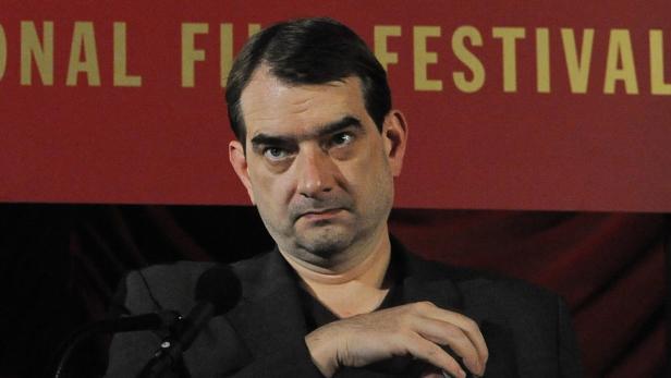 Ein Mann steht vor einem roten Hintergrund mit der Aufschrift „National Film Festival“.