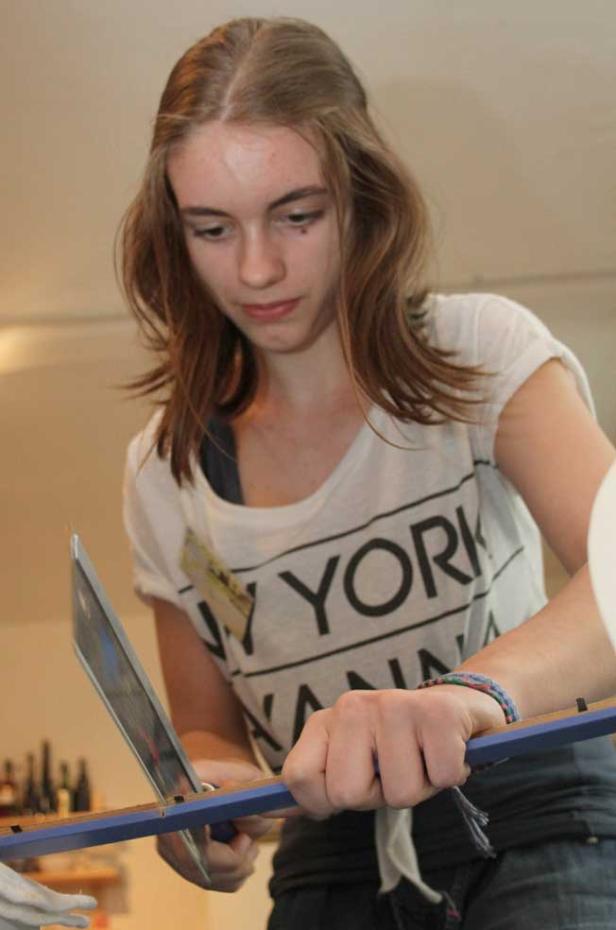 Eine junge Frau arbeitet mit einem Glasschneider an einem Werkstück.