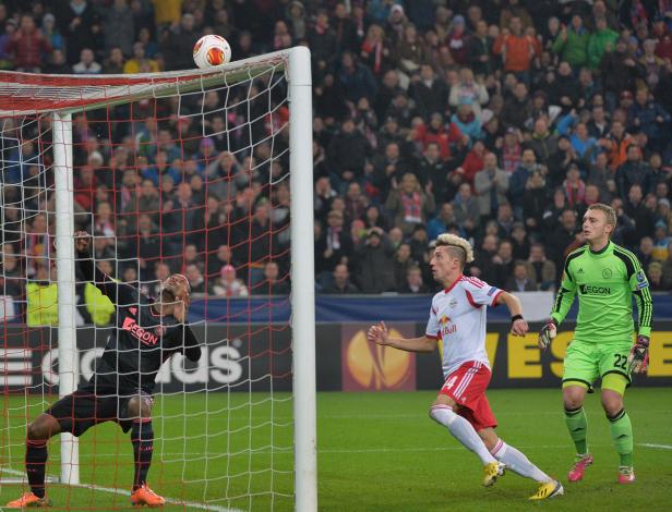 Ein Fußballspieler von RB Leipzig versucht, ein Tor zu erzielen, während der Torwart von Ajax zusieht.