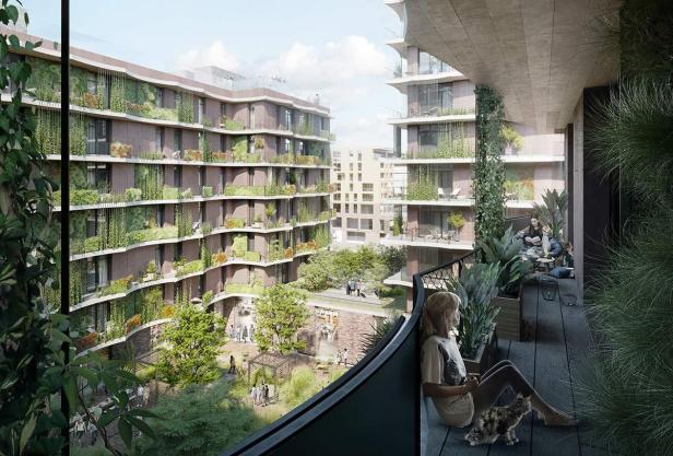 Eine Frau sitzt mit einer Katze auf einem begrünten Balkon mit Blick auf einen Innenhof.