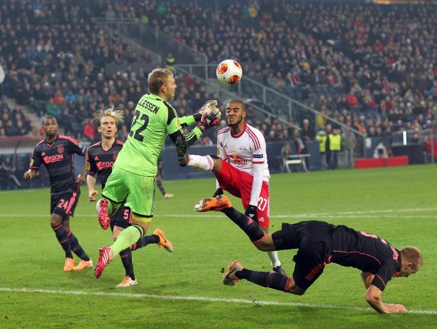 Ein Fußballspieler tritt den Ball, während der Torwart versucht, ihn abzuwehren.