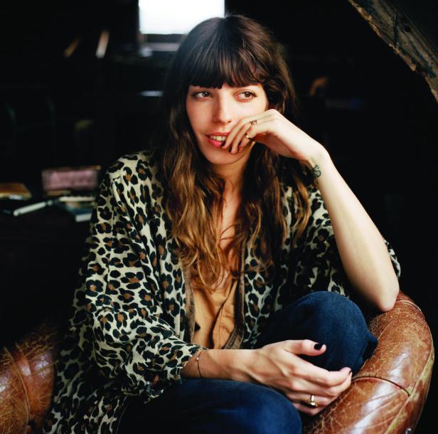 Eine Frau mit Leopardenmuster-Jacke sitzt in einem Ledersessel.