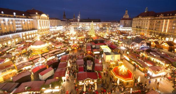 Der Dresdner Striezelmarkt mit vielen Buden und Lichtern in der Abenddämmerung.