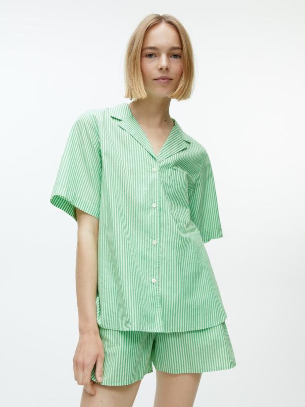 Eine Frau trägt einen grün-weiß gestreiften Pyjama.
