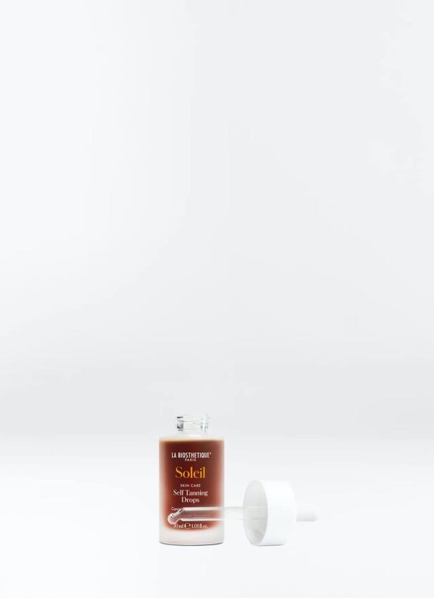 Eine geöffnete Flasche „Soleil Self Tanning Drops“ von La Biosthétique mit Pipette liegt daneben.