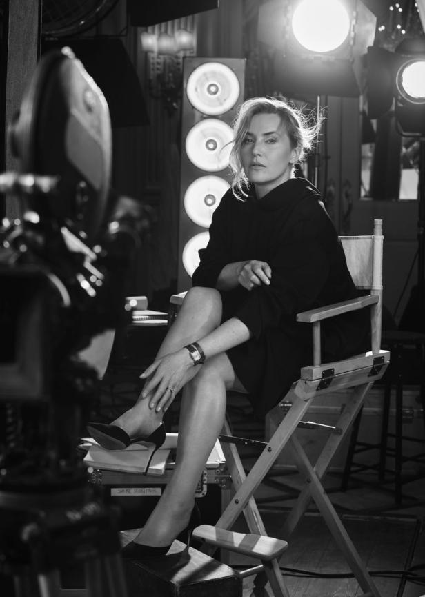Kate Winslet sitzt auf einem Regiestuhl in einem Filmstudio.