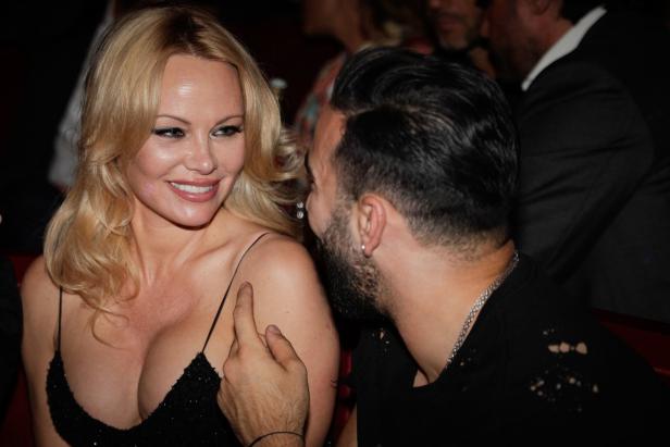 Pamela Anderson im Gespräch mit einem Mann bei einer Veranstaltung.