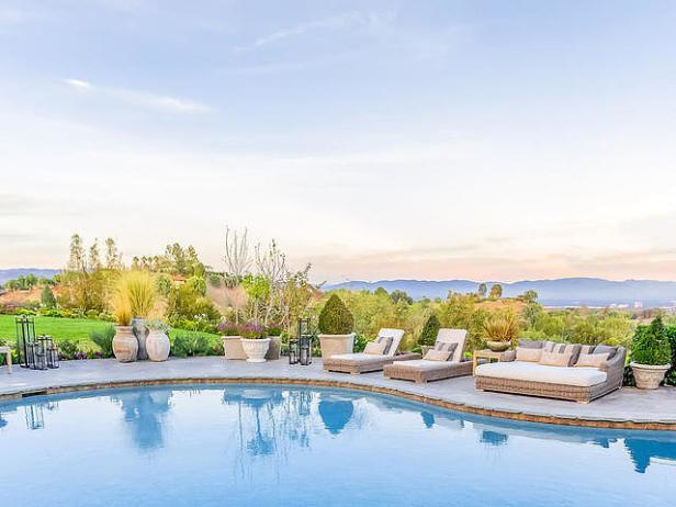 Ein Swimmingpool mit Liegestühlen und Blick auf eine grüne Landschaft.