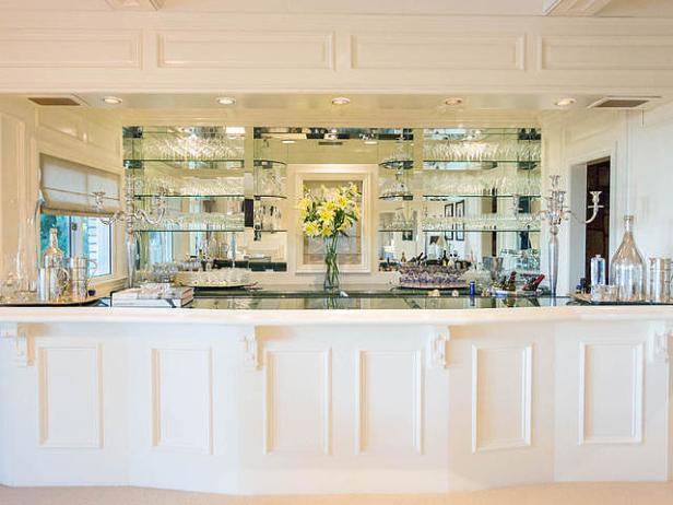 Eine Bar mit Spiegelwand, Glasregalen und gelben Lilien in einer Vase.