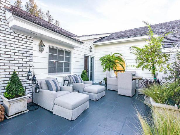 Eine Terrasse mit grauen Gartenmöbeln und üppiger Bepflanzung.