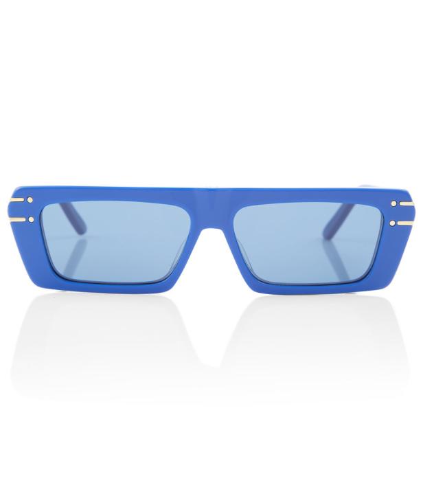 Eine blaue Sonnenbrille mit rechteckigen Gläsern liegt auf einem weißen Hintergrund.