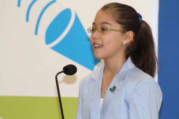 Ein junges Mädchen spricht bei einer Veranstaltung in ein Mikrofon.