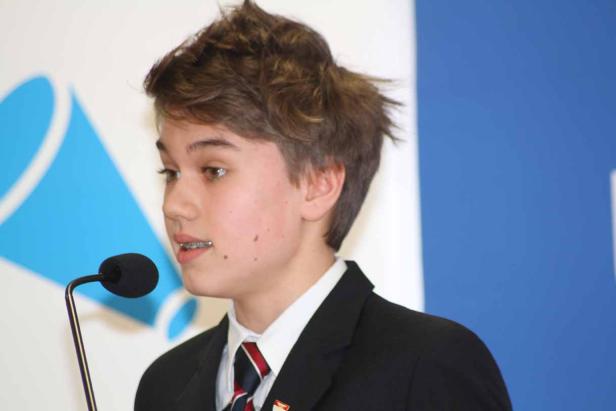 Ein junger Mann mit Zahnspange spricht in ein Mikrofon.