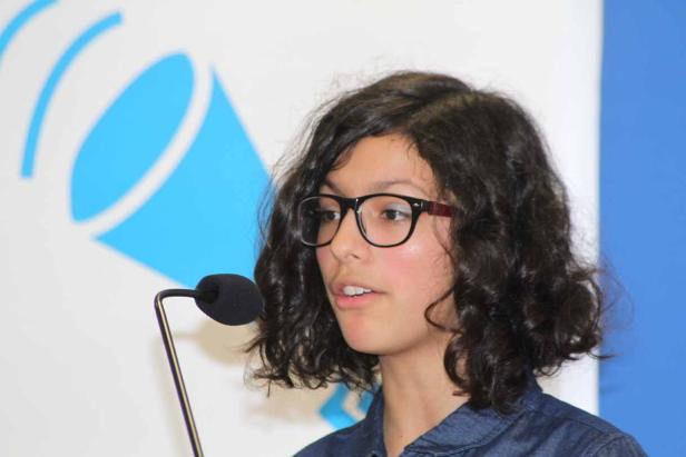 Eine junge Frau mit Brille spricht vor einem Mikrofon.