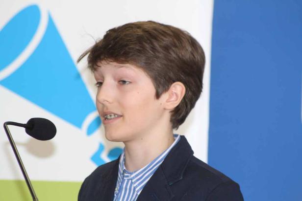 Ein junger Mann mit Zahnspange spricht an einem Mikrofon.