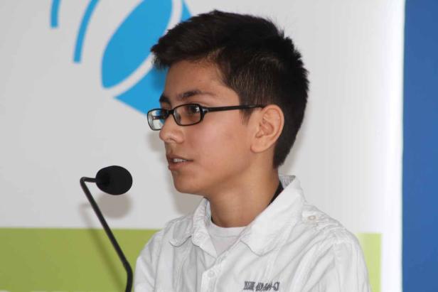 Ein junger Mann mit Brille spricht in ein Mikrofon.