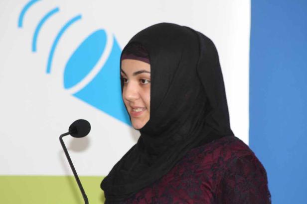 Eine Frau mit Hijab spricht an einem Mikrofon.