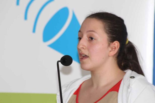 Eine junge Frau spricht vor einem Mikrofon.