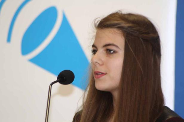 Eine junge Frau spricht vor einem Mikrofon.