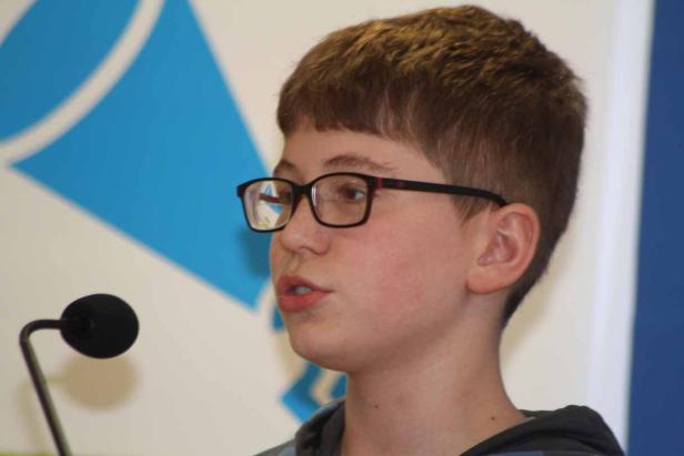 Ein junger Mann mit Brille spricht in ein Mikrofon.