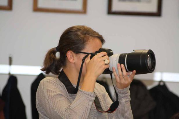 Eine Frau mit Brille fotografiert mit einer Canon-Kamera und einem Teleobjektiv.