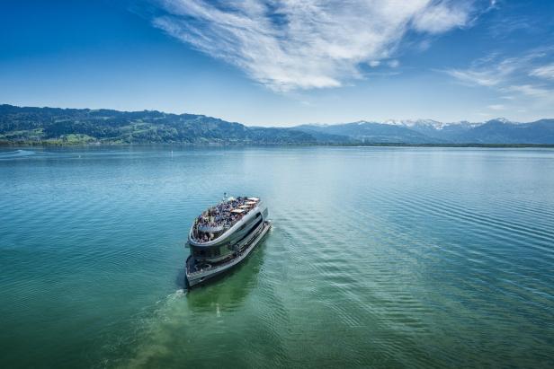 Ein Ausflugsschiff fährt auf einem See vor einer Bergkulisse.