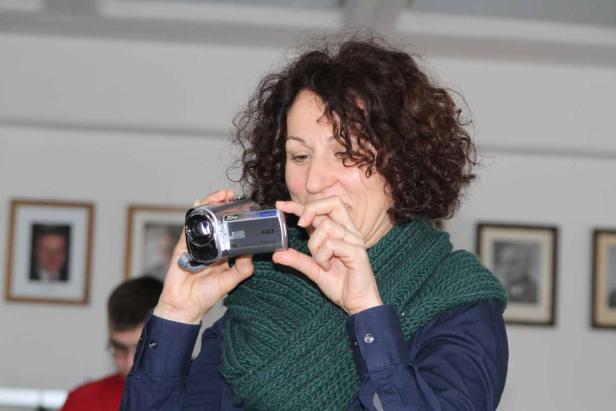 Eine Frau mit lockigem Haar filmt mit einer kleinen Videokamera.