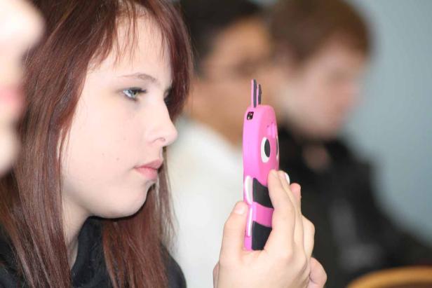 Ein junges Mädchen betrachtet ein pinkfarbenes Handy mit einem ungewöhnlichen Design.