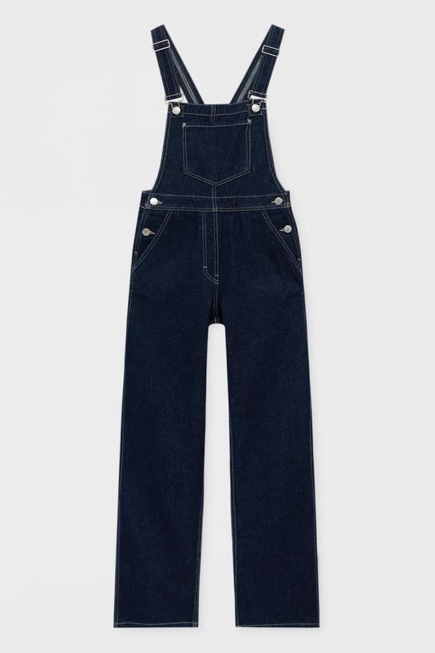 Eine dunkelblaue Jeans-Latzhose vor einem weißen Hintergrund.