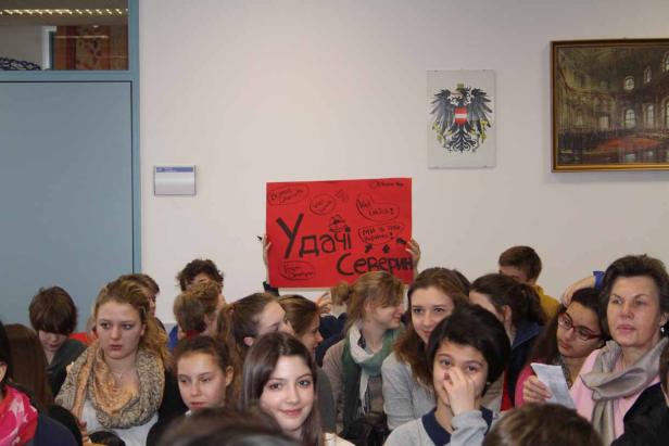 Eine Gruppe von Menschen hält ein rotes Schild mit der Aufschrift „Удачі Северин“.