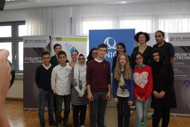 Eine Gruppe von Schülerinnen und Schülern posiert vor Bannern der HTL Wien 10.