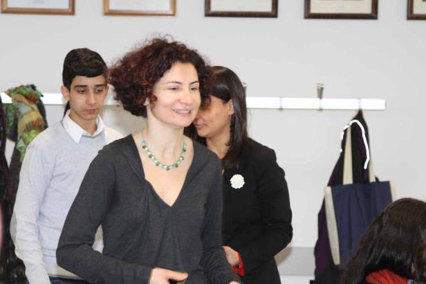 Eine Frau mit lockigem Haar und einer bunten Halskette lächelt.