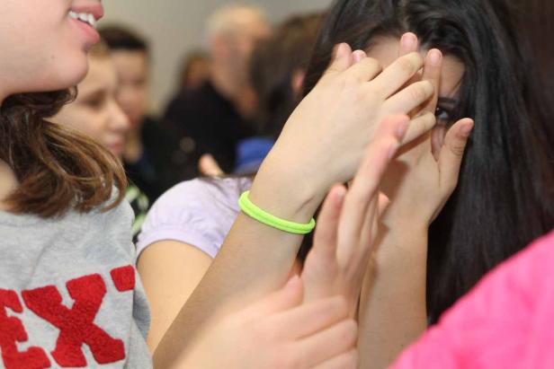 Ein junges Mädchen versteckt ihr Gesicht hinter ihren Händen.