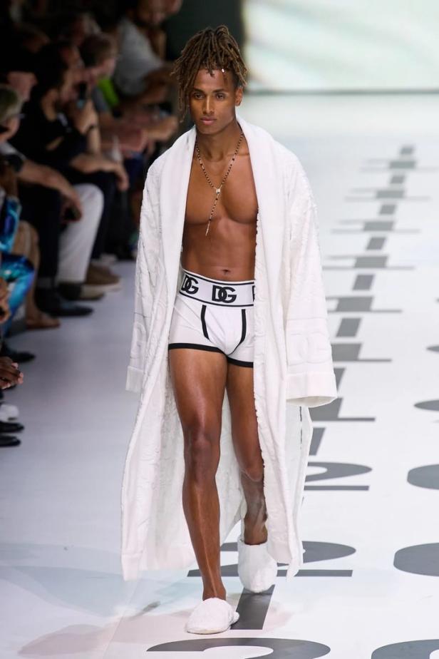 Ein Mann mit Dreadlocks trägt einen Bademantel und Unterwäsche von Dolce & Gabbana auf dem Laufsteg.