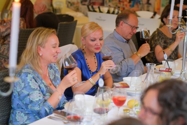 Mehrere Personen sitzen an einem Tisch und genießen Wein.
