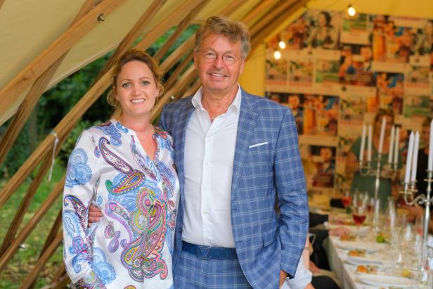 Ein Mann im blauen Anzug und eine Frau mit gemusterter Bluse posieren für ein Foto.