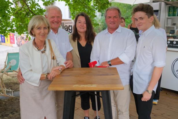 Eine Gruppe von fünf Personen steht um einen kleinen Tisch im Freien.