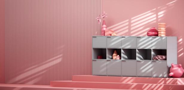 Ein graues Regal mit rosa Dekorationen steht vor einer rosa Wand.